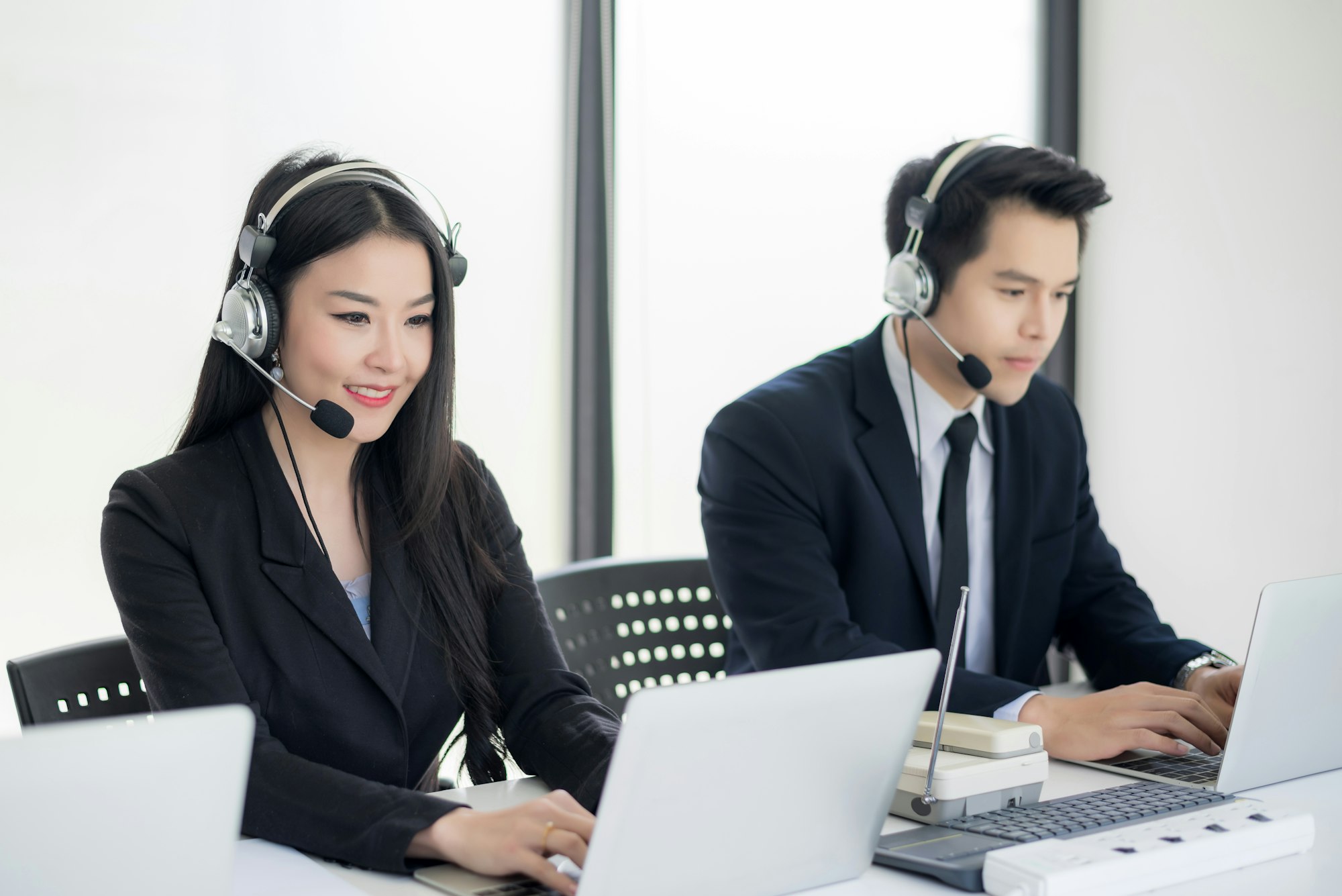 Operator in headphones with microphone consulting client on laptop in customer support service.